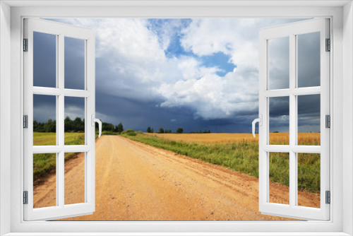 Fototapeta Naklejka Na Ścianę Okno 3D - Road and cereal field against dark stormy clouds