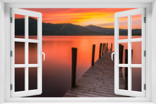 Fototapeta Naklejka Na Ścianę Okno 3D - Vibrant orange/red long exposure sunset over Derwentwater in the English Lake District. The tourist-popular Ashness jetty can be seen in the foreground.