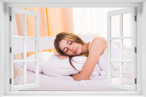 A sleeping woman is lying in bed with her head on the pillow and hands under it.