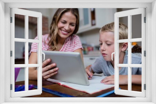 Mother using a digital tablet while helping son with his homework