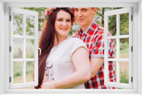 Pregnant woman in blue jeans and a T-shirt with her husband on the mountains background. Future parents