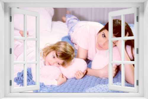 Romantic atmosphere mother and daughter hugging pink soft hearts in bed