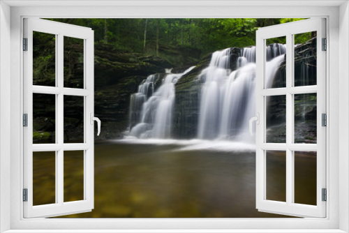 Fototapeta Naklejka Na Ścianę Okno 3D - A long exposure of a waterfall scene in a forest of green trees.