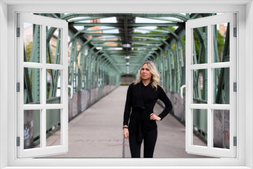 Beautiful blonde girl with black leggings standing on a bridge