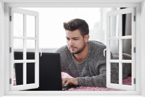 Man using laptop while lying on floor at home