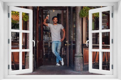 Smiling young man standing at the door of a cafe