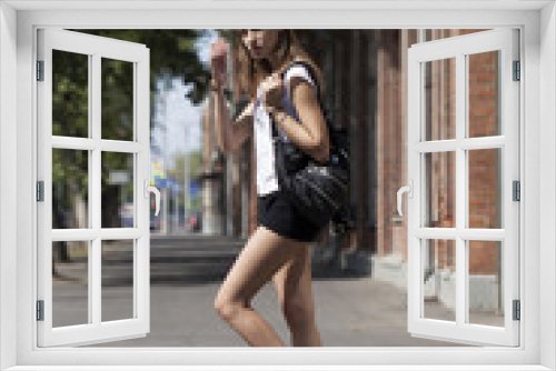 Young beautiful woman in a blue dress walking on the summer stre