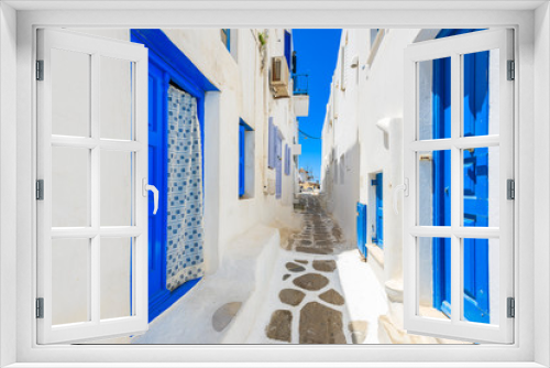 Fototapeta Naklejka Na Ścianę Okno 3D - A view of whitewashed street with blue doors in Mykonos town, Cyclades islands, Greece