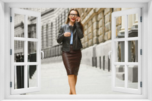 Businesswoman walking down the street while talking on smart pho