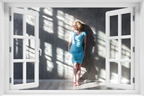 Smiling blond woman leaning on the wall and looking on sunlight