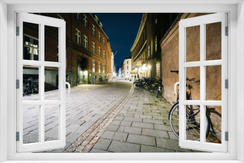 Fototapeta Naklejka Na Ścianę Okno 3D - Bicycle parked along a narrow street at night, in Copenhagen, De