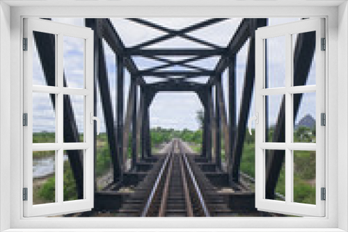 Fototapeta Naklejka Na Ścianę Okno 3D - view of the length of railway among old steel bridge with green tree at left and right side of railway,filtered image, light effect added, selective focus