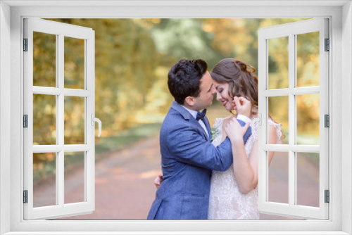 Handsome brunette groom touches bride's face while they pose in