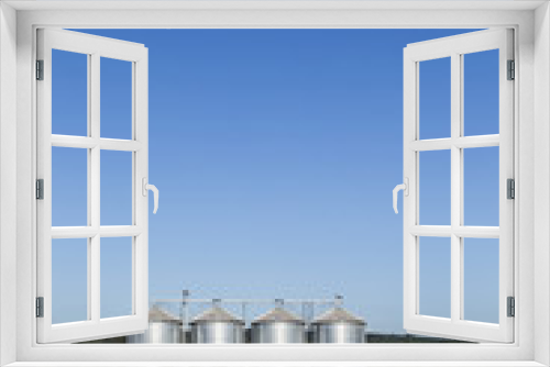 Fototapeta Naklejka Na Ścianę Okno 3D - four silver silos in field under   blue sky