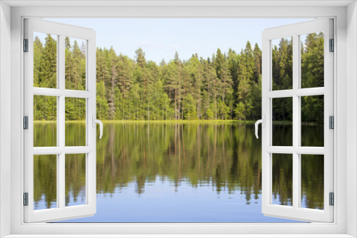Fototapeta Naklejka Na Ścianę Okno 3D - Silent evening by the lake. The sun is about to go down in Finland during late summer evening. The water is reflecting nicely the forest in the background.