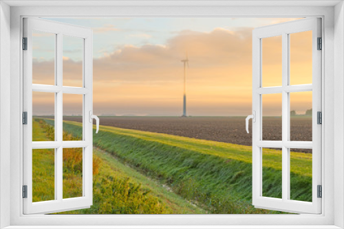 Fototapeta Naklejka Na Ścianę Okno 3D - Wind turbine in a foggy field at sunrise