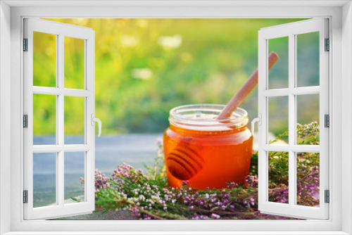Fototapeta Naklejka Na Ścianę Okno 3D - Honey in a glass jar with flowers melliferous herbs on a wooden surface. Honey with flowers of juniper