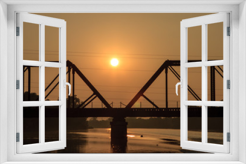 Fototapeta Naklejka Na Ścianę Okno 3D - A backlit silhouette of a railroad tres-sel on a river at dawn