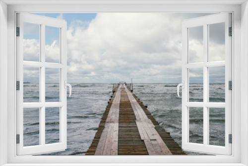 Fototapeta Naklejka Na Ścianę Okno 3D - Perspective view of a wooden pier on the seashore with stormy sea