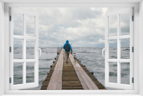 Fototapeta Naklejka Na Ścianę Okno 3D - man walking on wooden pier on the background of stormy sea
