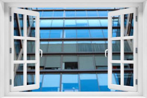 Fototapeta Naklejka Na Ścianę Okno 3D - Facade with glass wall of modern office building with many large panoramic windows with gray curtains in business cluster top section front view close-up