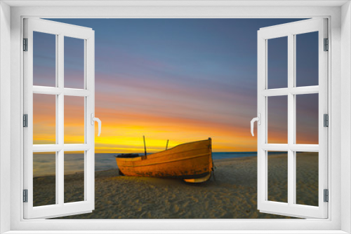 Fototapeta Naklejka Na Ścianę Okno 3D - Pomarańczowa łódź rybacka na plaży o zachodzie słońca