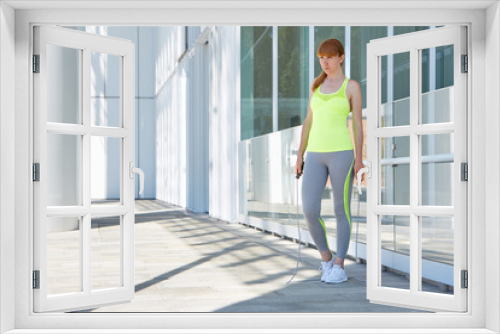 Woman with jump rope and white modern architecture in the city