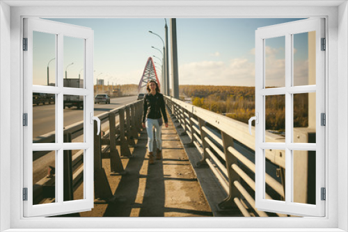 Fototapeta Naklejka Na Ścianę Okno 3D - girl goes on road bridge. lonely young woman in black Leather jacket autumn, walking over the bridge which goes transport.
