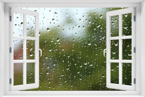 Fototapeta Naklejka Na Ścianę Okno 3D - Rain drops on window with building and green tree in background 