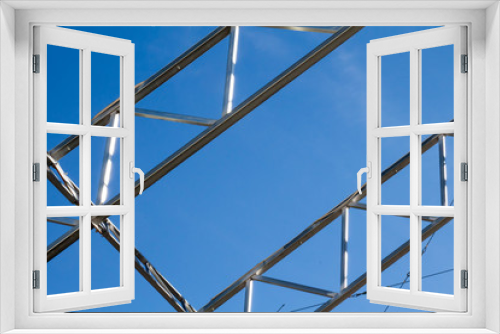 Fototapeta Naklejka Na Ścianę Okno 3D - Two metal trusses against blue sky