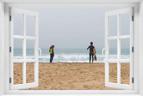 Fototapeta Naklejka Na Ścianę Okno 3D - Two surfers stand ashore ocean. Fellow and girl.