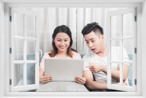 Young couple surfing on internet with laptop. Modern white apartment in background