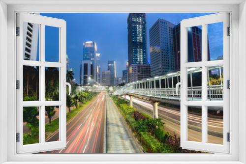 Fototapeta Naklejka Na Ścianę Okno 3D - Light trail of vehicle traffic in Jakarta main road, Sudirman Street,  Jakarta. Also showing row of beautiful pedestrian bridge in the middle of the road. Urban Skyline, Building Exterior