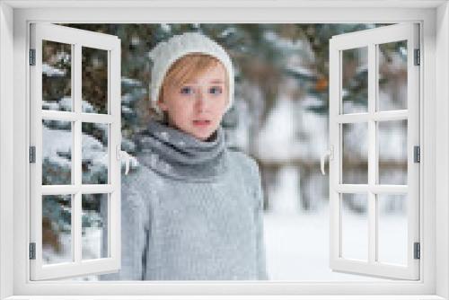 Beautiful girl in a white hat and mittens in the winter snowy fo