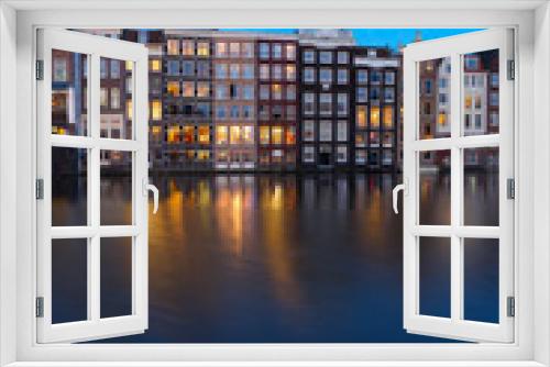 Fototapeta Naklejka Na Ścianę Okno 3D - Houses facades over canal with reflections illuminated at blue night, Amsterdam, Netherlands