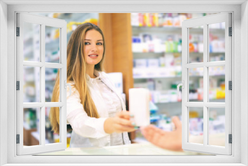 Attractive smiling pharmacist giving her client pills at the local drugstore