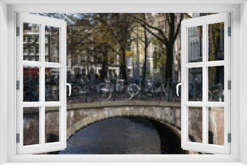 Fototapeta Naklejka Na Ścianę Okno 3D - Brown bridge with bikes over the canal in autumn in the day in Amsterdam