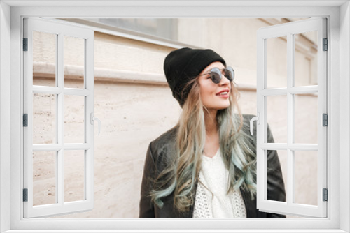 Happy lady wearing hat and sunglasses walking on the street.