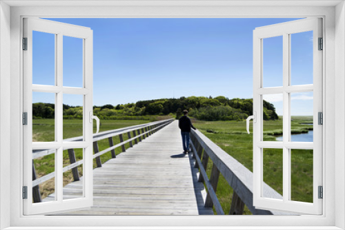 Fototapeta Naklejka Na Ścianę Okno 3D - man walking along boardwalk over salt water marsh on Cape Cod