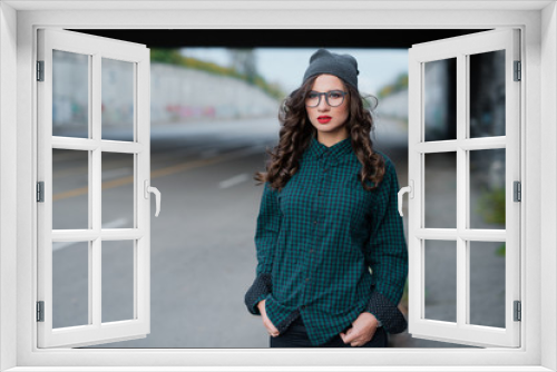 Nice girl with curly hair and red lips. Dressed in a dark green shirt and a gray hat on his head. He wears glasses for vision.