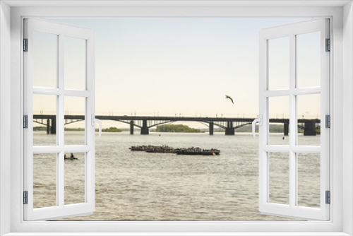 Fototapeta Naklejka Na Ścianę Okno 3D - view of the river from the embankment, the structure in the water, the boat is sailing, a bird flying on the background of the bridge