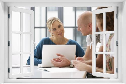 Three businesspeople using laptop while a meeting