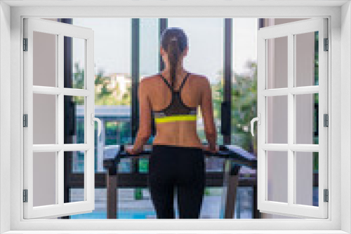 Woman running on the treadmill in the gym with a great poolside view