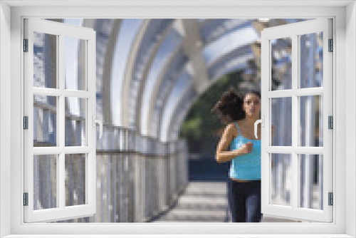 young beautiful athletic sport woman running and jogging crossing modern metal city bridge