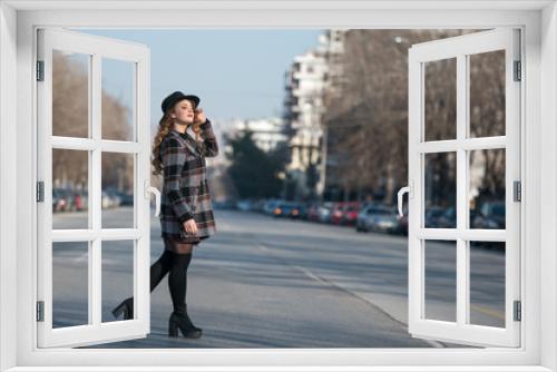 Fashion teen in city wear coat and hat walking in profile at the middle of the highway