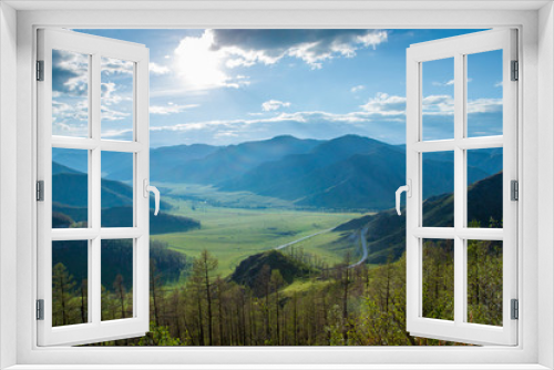 Fototapeta Naklejka Na Ścianę Okno 3D - A beautiful mountain landscape. Gorgeous green valley and the beautiful hills illuminated by the sun, in the valley is a winding road. Blue sky and clouds. Journey to the Altai mountains, Russia