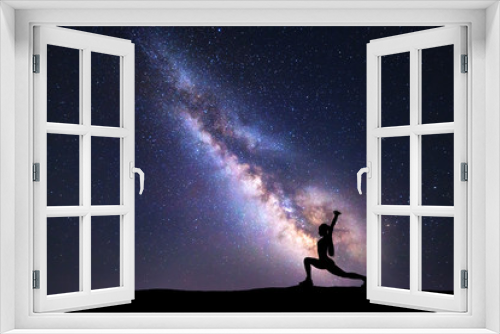 Fototapeta Naklejka Na Ścianę Okno 3D - Milky Way with silhouette of a standing woman practicing yoga on the mountain. Beautiful landscape with meditating girl against night starry sky with milky way. Amazing galaxy. Universe. Fitness