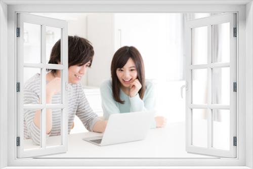 young asian couple using laptop in kitchen