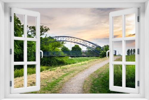 Fototapeta Naklejka Na Ścianę Okno 3D - Deserted Path and a Metal Bridge through the Countryside at Sunset.