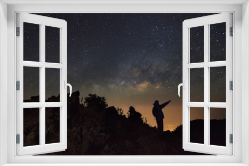 Fototapeta Naklejka Na Ścianę Okno 3D - A Man is standing next to the milky way galaxy pointing on a bright star at Doi Luang Chiang Dao with Thai Language top point signs. Long exposure photograph.With grain